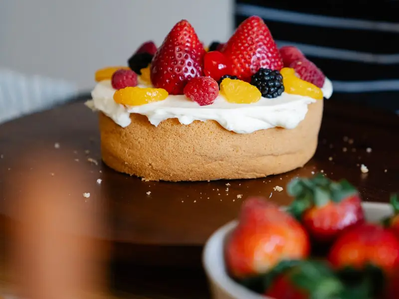 Hands finishing a fruit tart with fresh strawberries