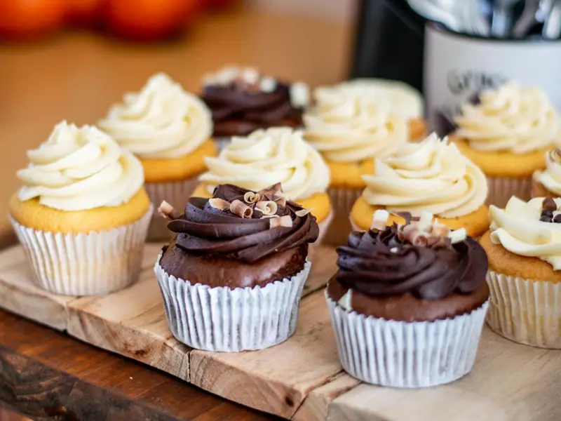 Vanilla and chocolate cupcakes with swirled buttercream on a wooden board