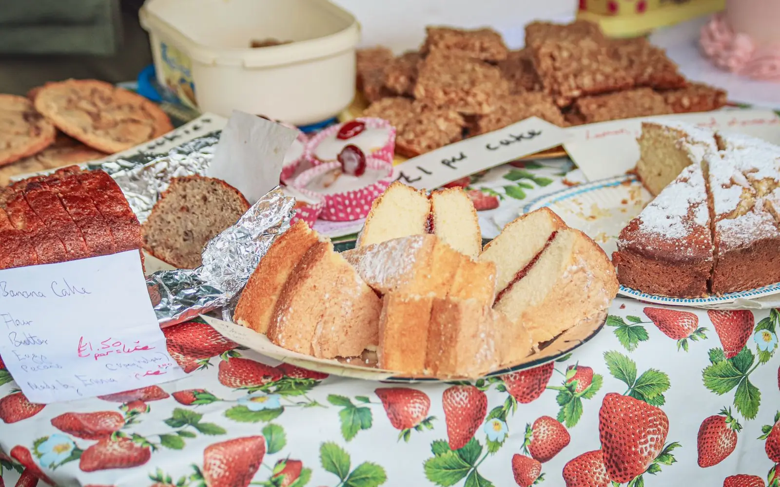 A table of homemade cakes, loaves and biscuits laid out for a bake sale